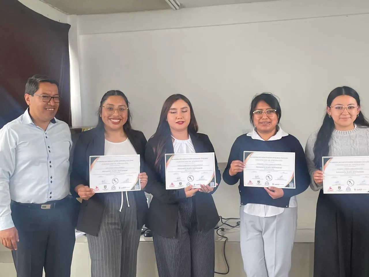 Graduadas muestran su certificado junto al director académico de la Academia ITALIANO.