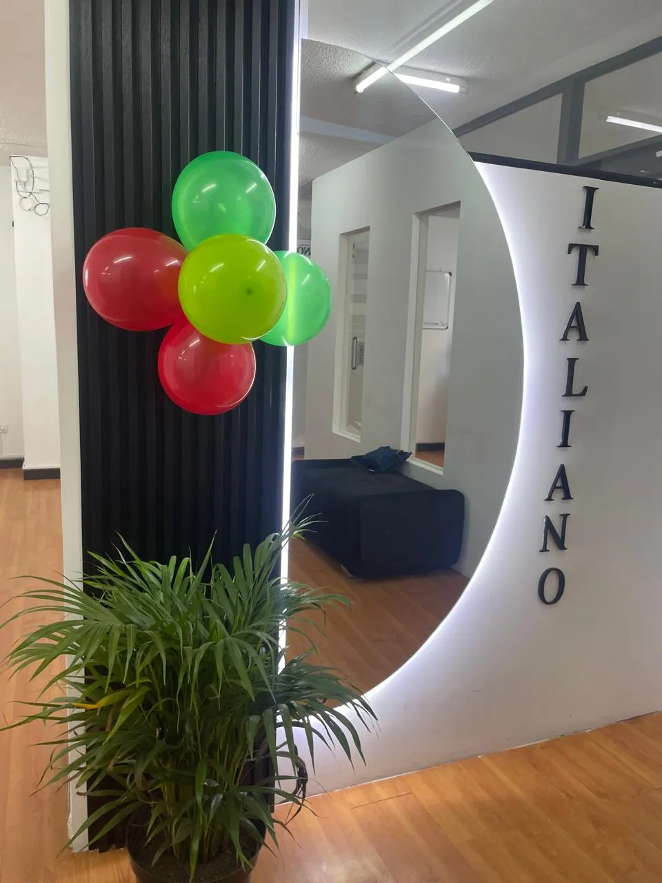 Recepción de la Academia ITALIANO con el logotipo iluminado en la pared de ingreso
